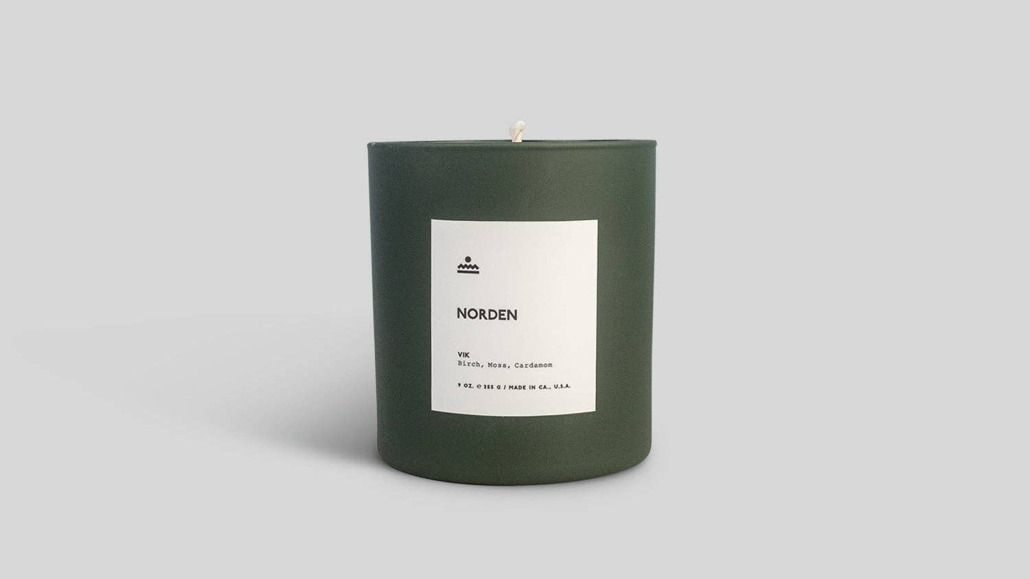 Green candle with a white label on a light gray background