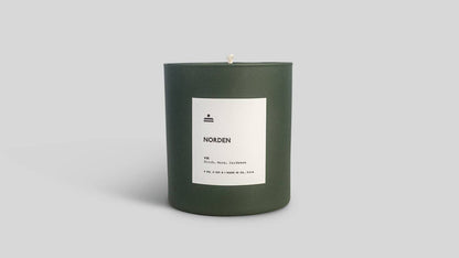 Green candle with a white label on a light gray background