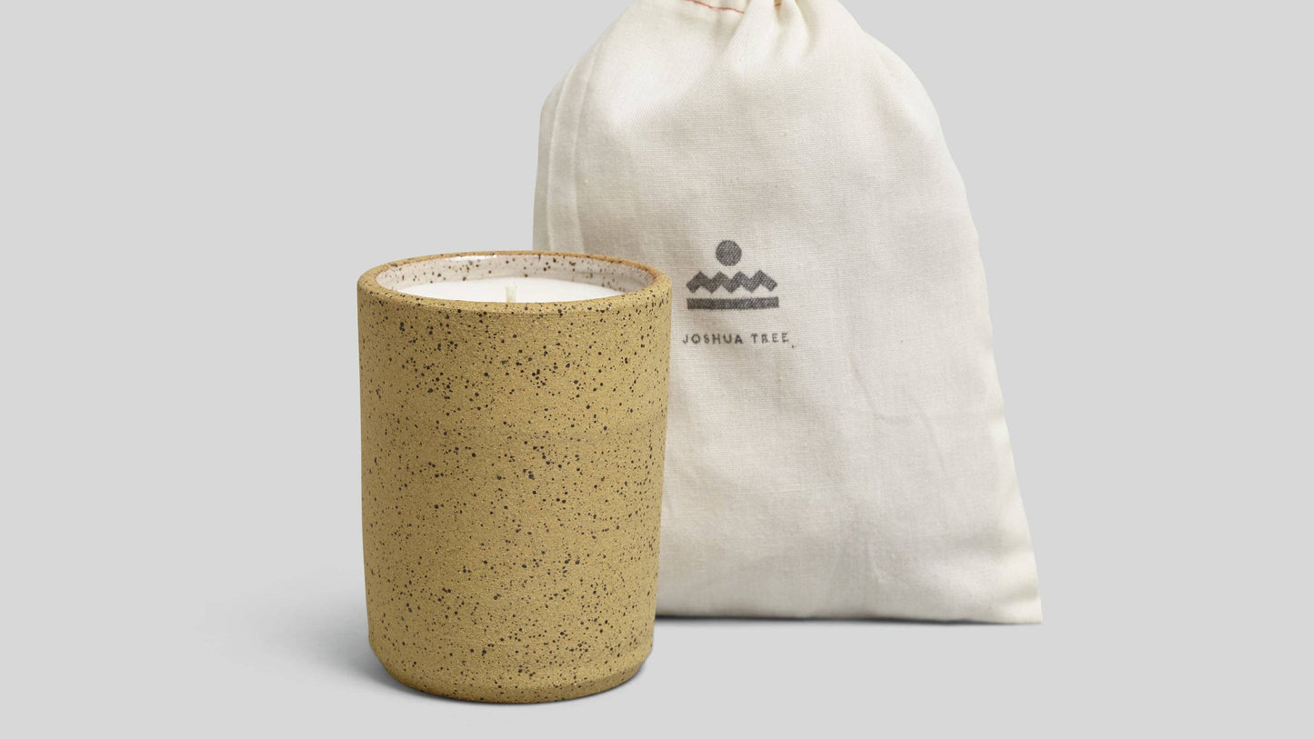 Speckled ceramic jar with a white drawstring bag on a light gray background